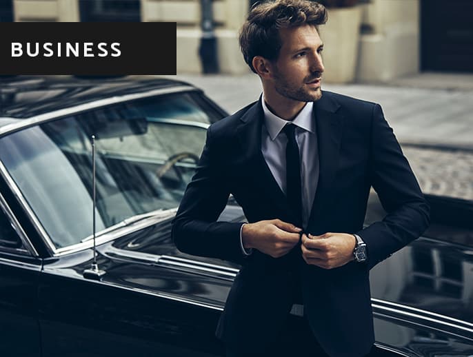 Mann im Business-Outfit vor edlem Auto